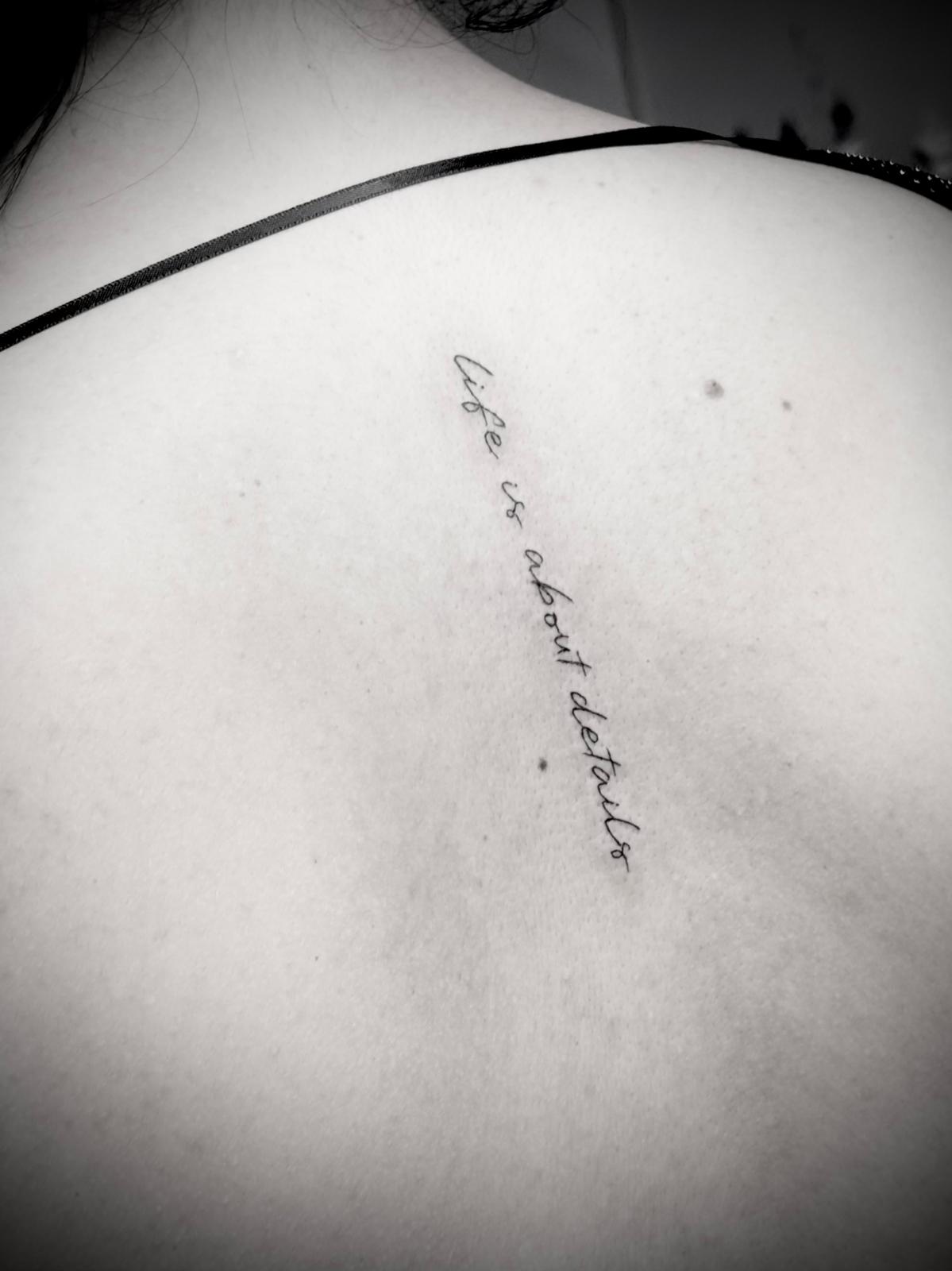 Tatuagem fine line lettering 'Life is about details' nas costas por Heltattoo