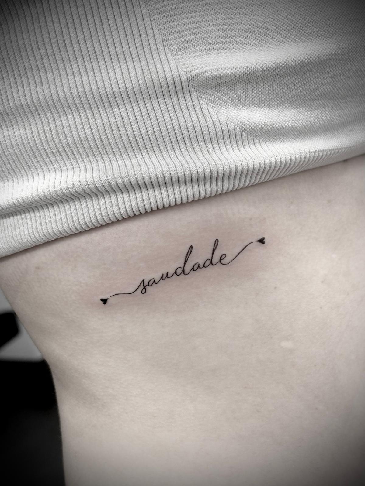 Tatuagem lettering 'saudade' nas costelas por Heltattoo