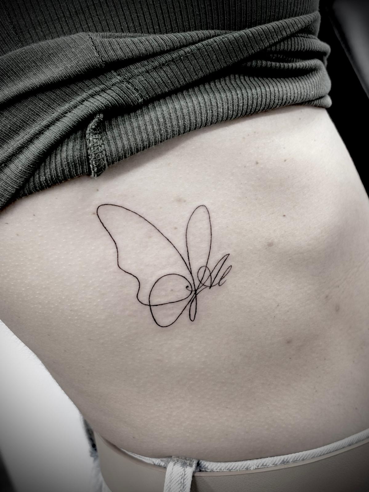 Tatuagem fine line borboleta com inicial nas costelas por Heltattoo