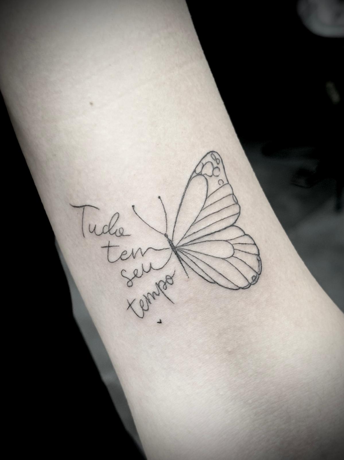 Tatuagem fine line de borboleta com frase 'Tudo tem seu tempo' por Heltattoo